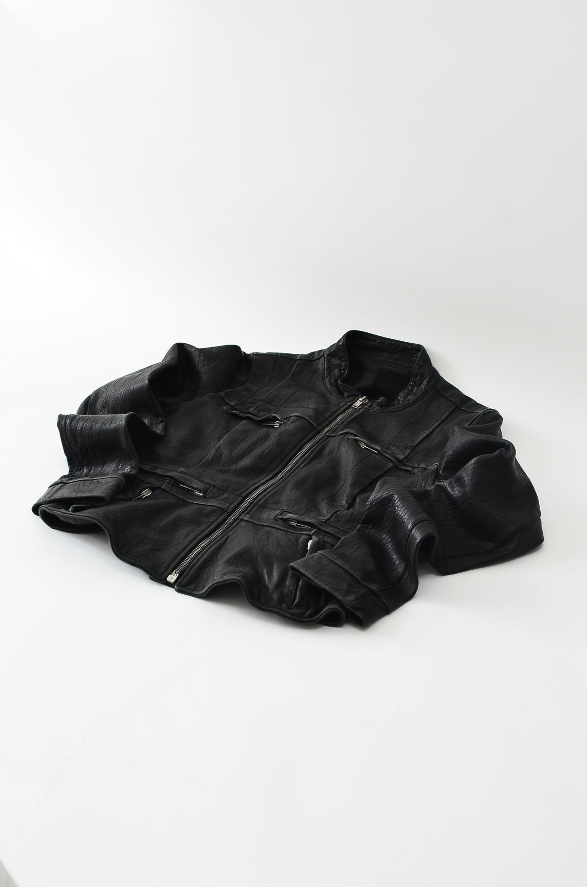 A black leather jacket laid flat on a light background.