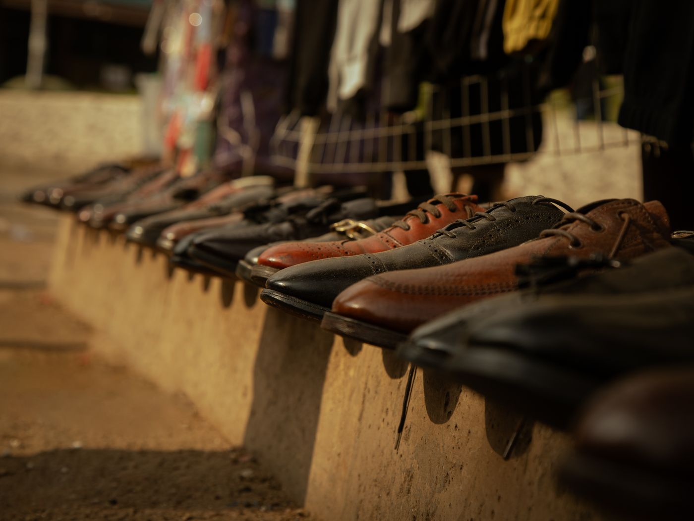 A row of finished leather shoes lined up on a ledge.