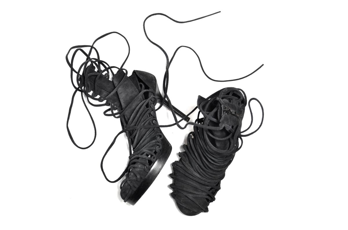 Black leather laced sandals on a white background.